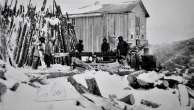 Men splitting logs for construction in winter