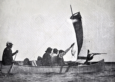 Cree men hunting in a large canoe