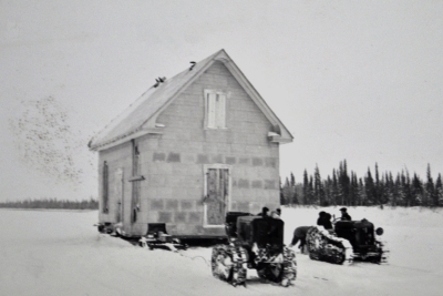 Tractors moving a house on skids during winter