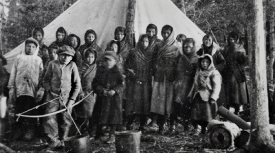Young Cree women, boys and girls in front of tent