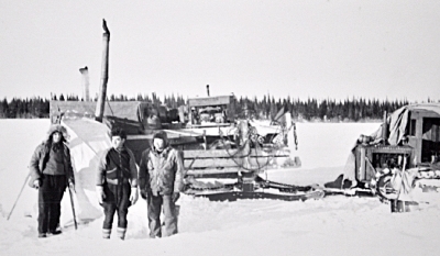 non-Cree men stand in front of a tractor sled train